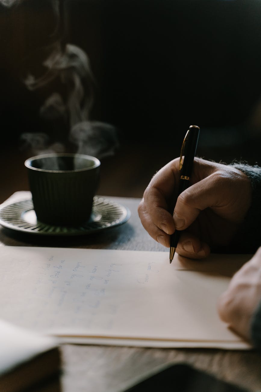 person writing a letter on table