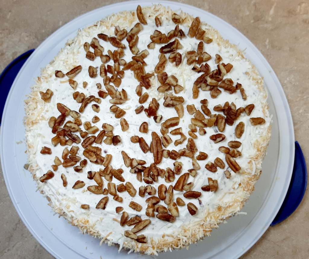 Italian Cream Cake with pecans on top sitting on white platter