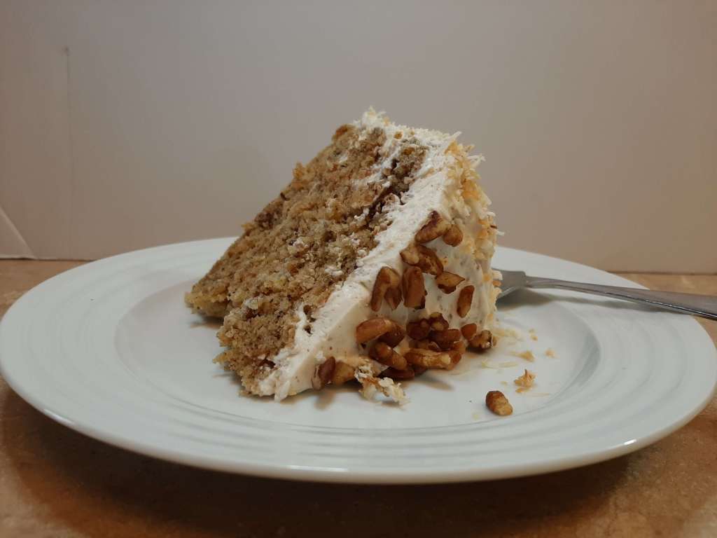 slice of Italian cream cake on white plate with fork on counter