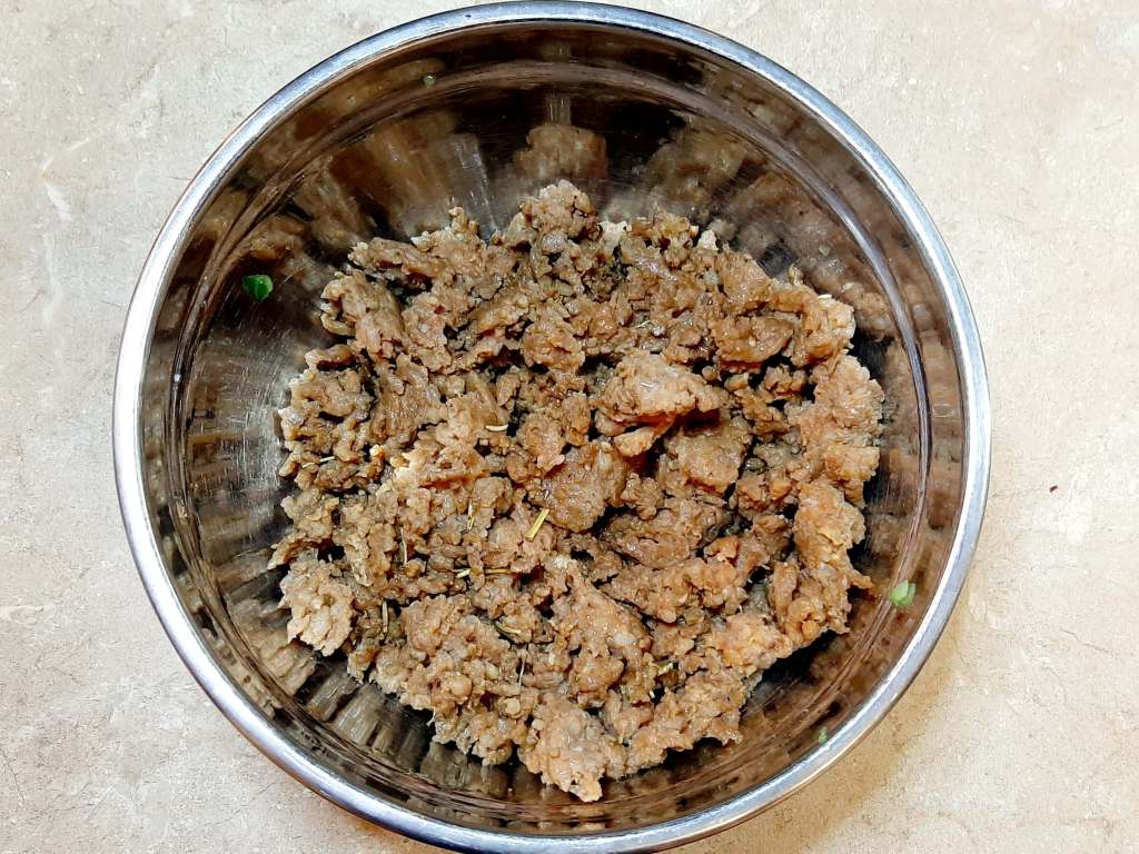 ground meat with spices in metal bowl