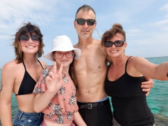 4 people standing in front of blue water