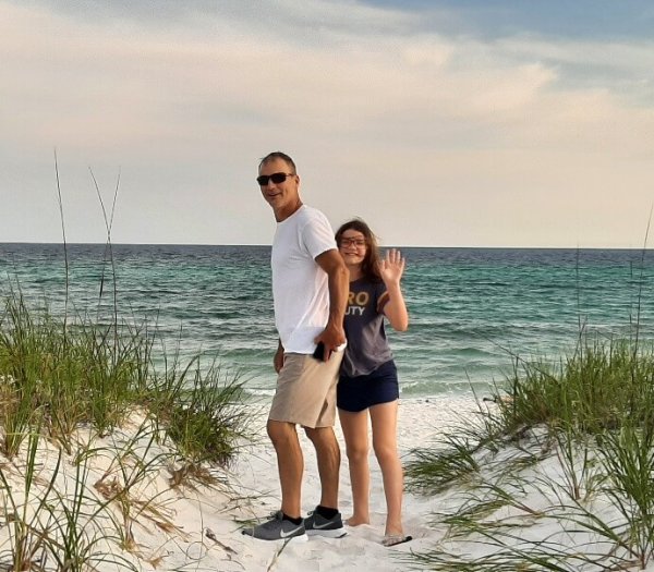 2 people standing on sandy shore in front of blue ocean