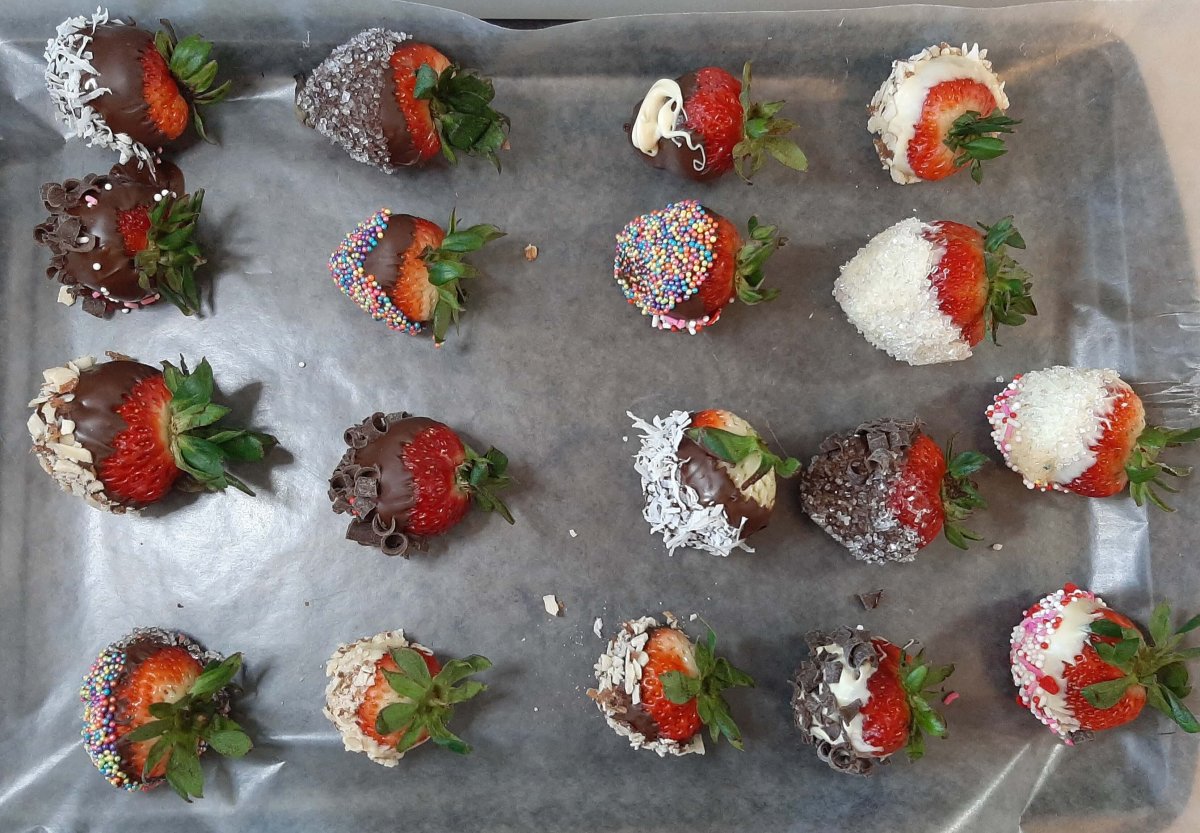 decorated chocolate covered strawberries on aluminum foil on a pan