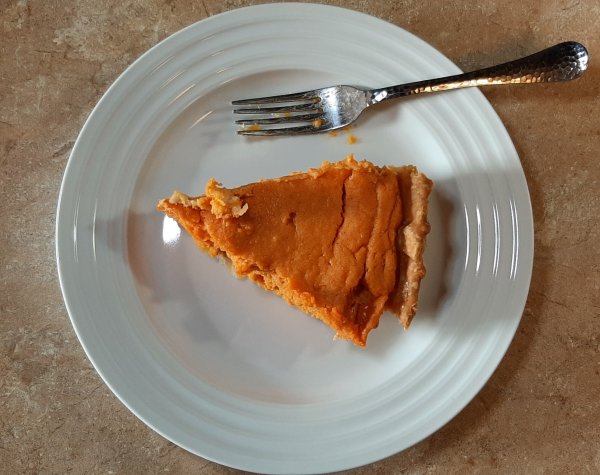 slice of sweet potato pie with fork on a white plate