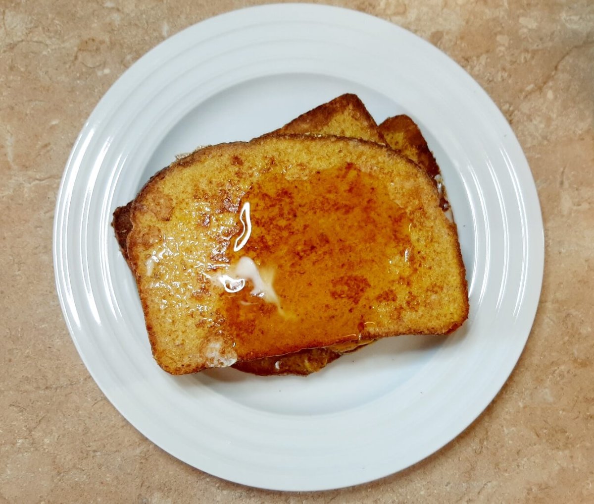 slices of French toast with syrup on white plate