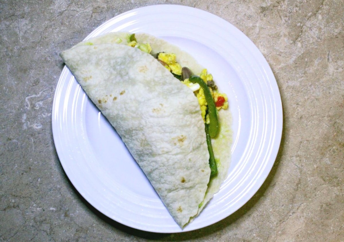 scrambled egg with sautéed vegetables in a tortilla on a white plate