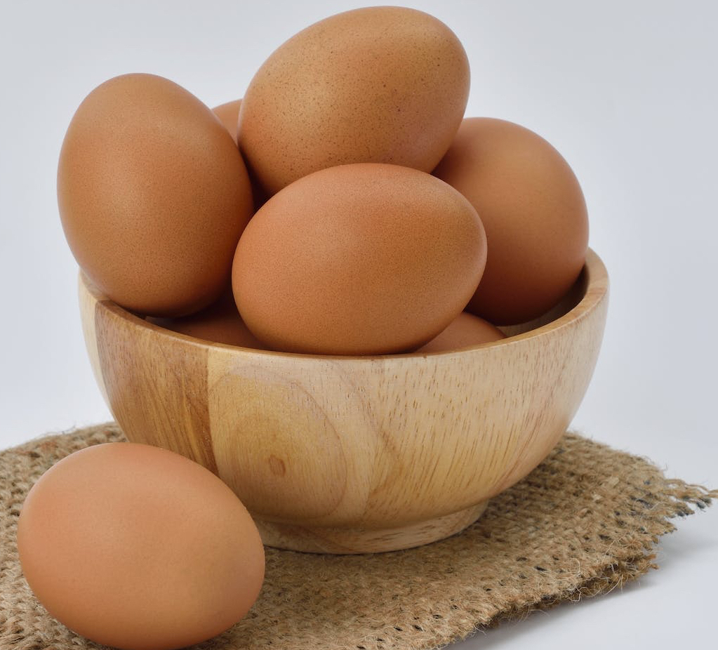 brown eggs on brown wooden bowl on beige knit textile