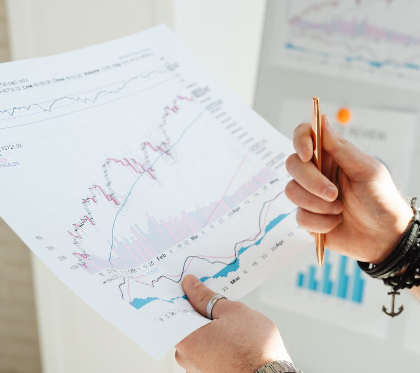 a person holding pen and paper with graphs