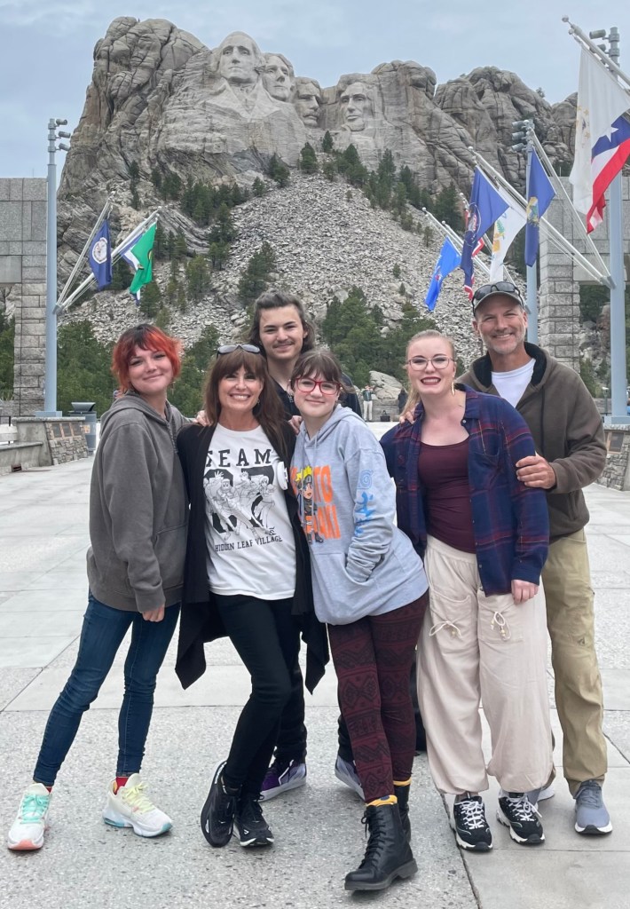 6 people posing for a picture in front of Mount Rushmore