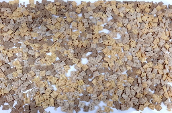 3 different colored and types of Chex mix cereal laid out on a flat and white surface