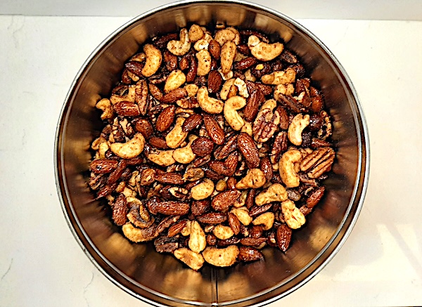mixed nuts sitting in a tin can on a white background