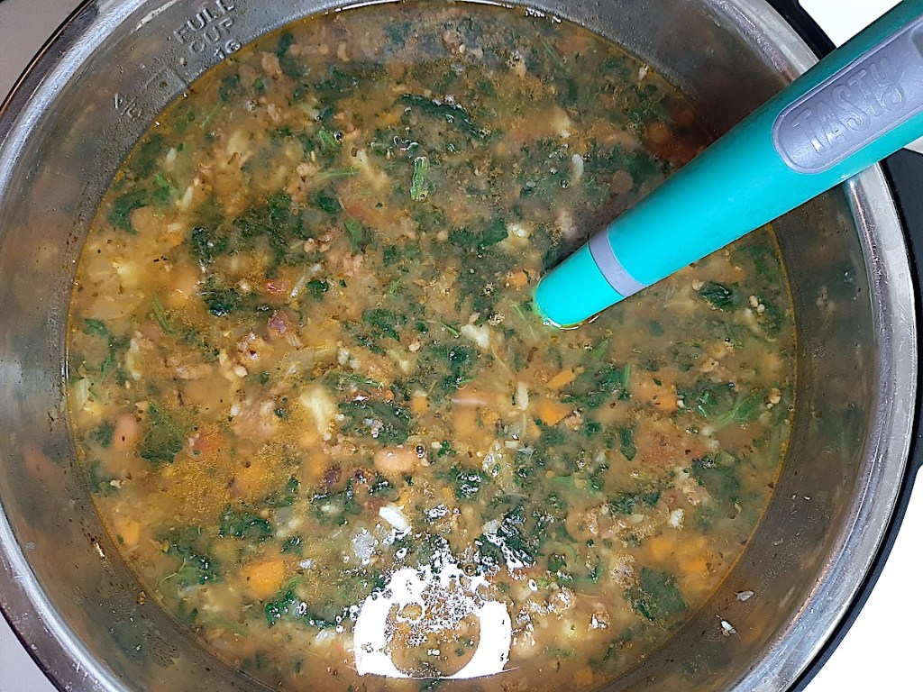 pot of soup with tomatoes, greens, tomatoes, and indistinguishable other items